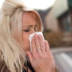 Woman blowing her nose into a tissue